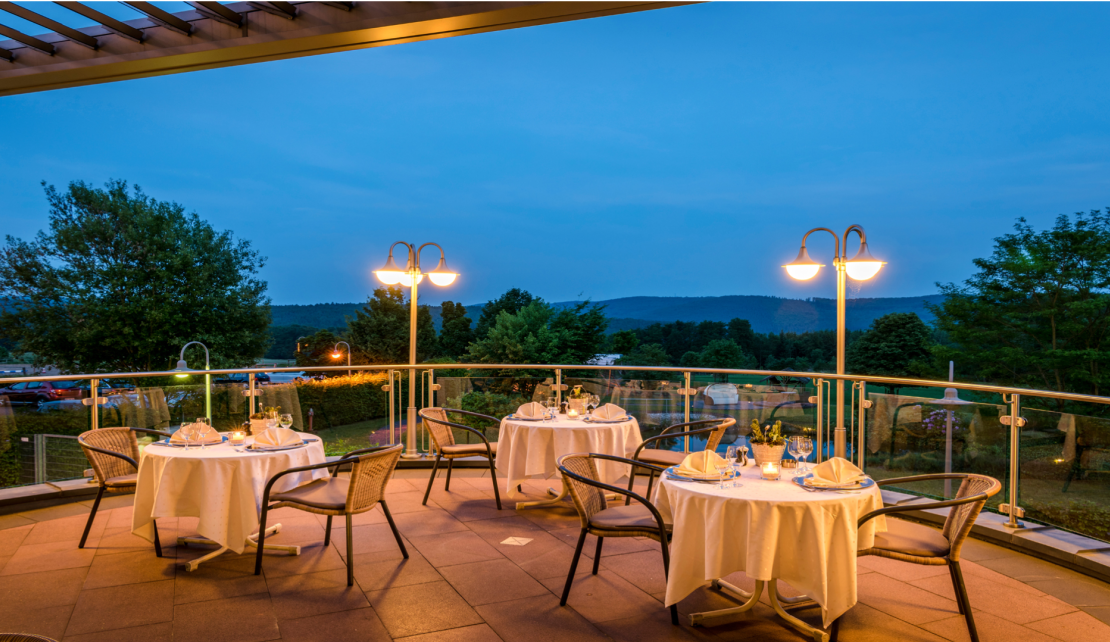 3 gedeckte Tische auf der Terasse bei Abenddämmerung